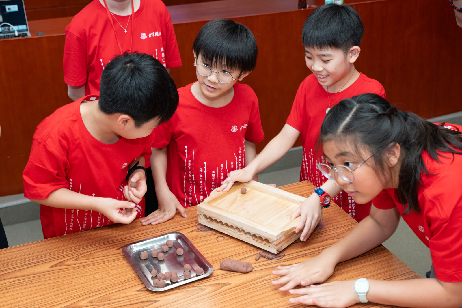 学生于北京同仁堂工作坊亲手使用搓药板制作传统药丸，从实作中体验中药制剂工艺的细致要求，感受传统制药技艺的匠心精神。